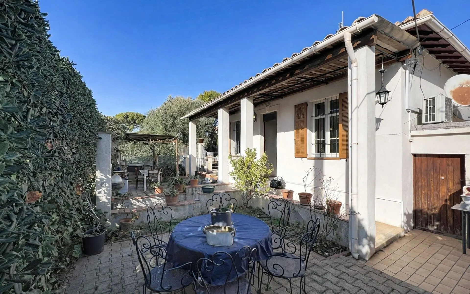Maison blanche aux volets en bois et sa terrasse ombragée, à Mouans-Sartoux (Alpes-Maritimes)